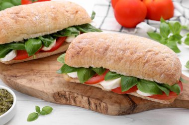 Nefis Caprese sandviçleri, mozarella, domates ve fesleğen beyaz ahşap masa, yakın plan.