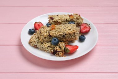 Lezzetli granola barlar ve böğürtlenler pembe ahşap masada