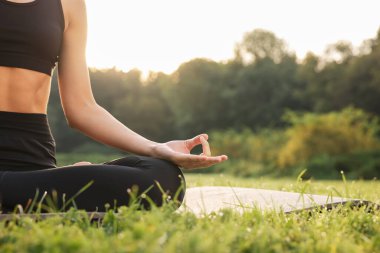 Dışarıdaki yoga minderinde Padmasana antrenmanı yapan bir kadın, yakın çekim ve mesaj için yer. Lotus pozu