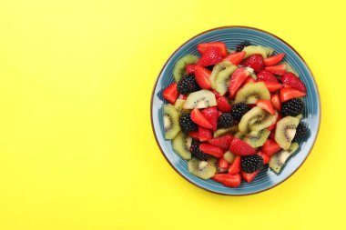 Sarı arka planda lezzetli meyve salatası tabağı, üst manzara. Metin için boşluk