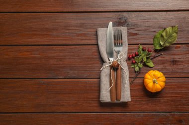 Peçete, çatal bıçak seti, balkabağı ve böğürtlen ahşap arka planda, düz yerde yazı için yer var. Şık sonbahar masa ayarları