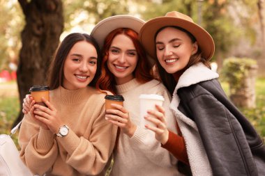 Parkta kağıt bardaklı mutlu arkadaşlar.