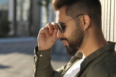 Dışarıda güneş gözlüklü yakışıklı bir adam, mesaj için yer var.