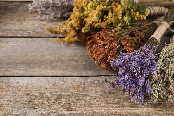 Bunches of different dry herbs on wooden table, closeup. Space for text