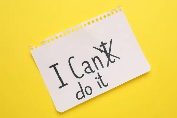 Motivation concept. Changing phrase from I Can\'t Do It into I Can Do It by crossing out letter T on yellow background, top view