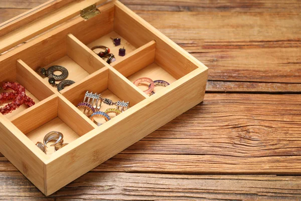 Jewelry box with many different accessories on wooden table. Space for text