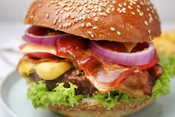 Delicious burger with bacon, patty and vegetables on plate, closeup