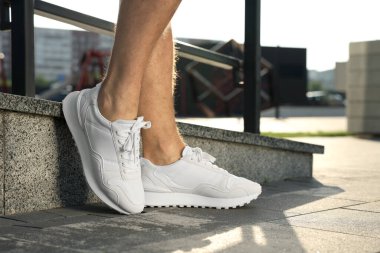 Parmaklıkların yanında şık ayakkabılar giyen bir adam, yakın plan.