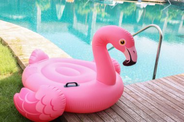 Lüks bir tatil köyünde yüzme havuzunun yanındaki tahta güvertede flamingo şeklinde süzül.