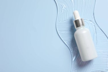 Açık mavi arka planda bir şişe kozmetik serumu. Metin için boşluk