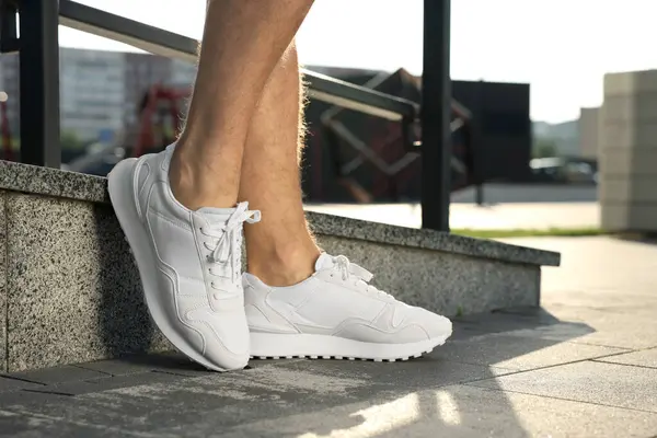 Parmaklıkların yanında şık ayakkabılar giyen bir adam, yakın plan.