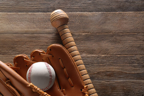 Baseball glove, bat and ball on wooden table, flat lay. Space for text