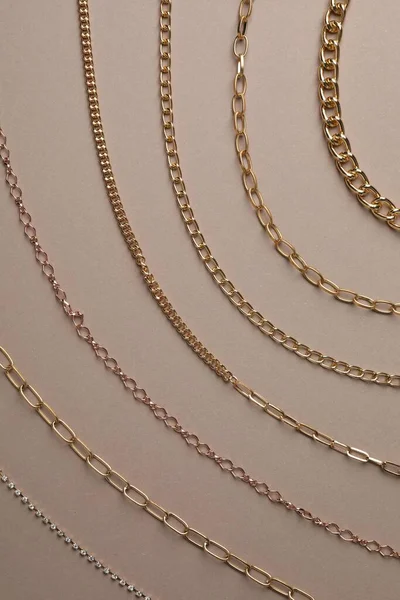 Różne Metalowe Łańcuchy Jasnobrązowym Tle Płaskie Układanie Luksusowa Biżuteria — Zdjęcie stockowe