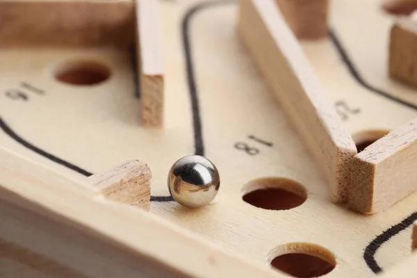 Wooden toy maze with metal ball, closeup