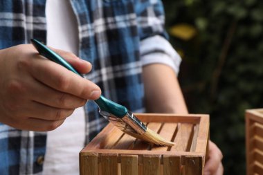 Ahşap sandığa vernik uygulayan adam arka planda bulanık, yakın plan