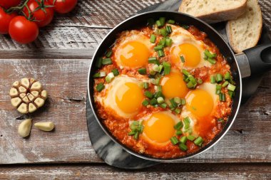 Lezzetli Shakshuka kızartma tavasında ahşap masada servis ediliyor.