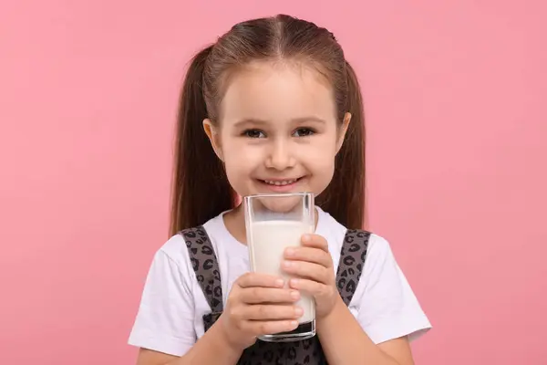 ピンクの背景に新鮮なミルクのガラスとかわいい少女 — ストック写真
