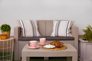 Terastaki rattan masada çay ve kruvasan ile açık havada kahvaltı.