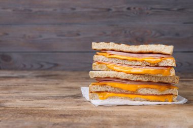 Ahşap masada jambon ve peynirli leziz ızgara sandviçler. Metin için boşluk