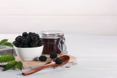 Taze böğürtlen, lezzetli reçel ve beyaz ahşap masada yapraklar. Metin için boşluk