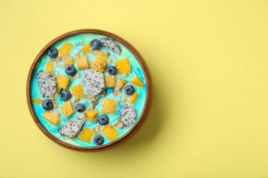 Sarı arka planda taze meyve, yaban mersini ve yulaf ezmesi ile nefis bir meyve suyu kasesi. Metin için boşluk