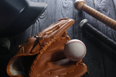 Beyzbol eldiveni, beyzbol sopası, top ve kask siyah tahta masada, yakın plan.