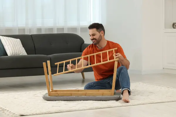 Man assembling shoe storage bench on floor at home