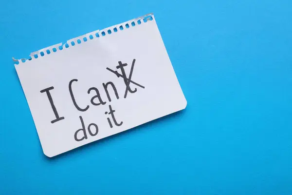 Motivation concept. Changing phrase from I Can\'t Do It into I Can Do It by crossing out letter T on light blue background, top view. Space for text