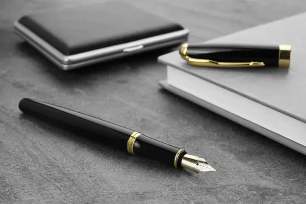 Κομψό Μαύρο Στυλό Σημειωματάριο Και Ταμπακιέρα Γκρι Υφή Τραπέζι Closeup — Φωτογραφία Αρχείου
