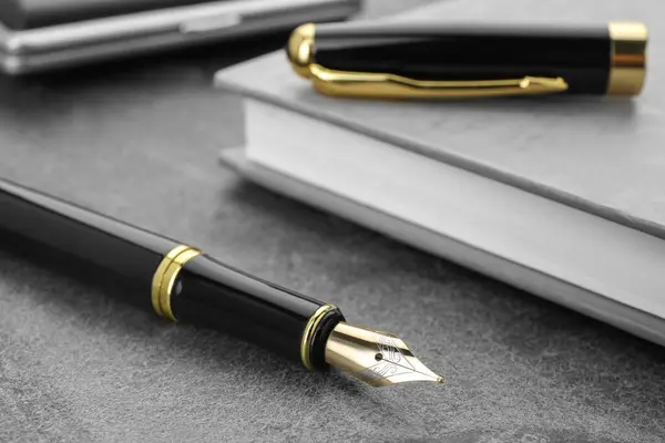 Κομψό Μαύρο Στυλό Στυλό Και Σημειωματάριο Γκρι Υφή Τραπέζι Closeup — Φωτογραφία Αρχείου