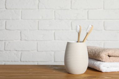 Bambu diş fırçaları tutacakta ve havlular ahşap masada. Metin için boşluk
