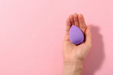 Pembe arka planda mor makyaj süngeri olan kadın, üst manzara. Metin için boşluk