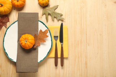 Hafif ahşap arka planda tabak ve çatal bıçak takımı olan şık bir sonbahar masası. Metin için boşluk