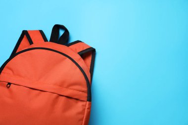 Açık mavi arka planda turuncu bir sırt çantası, üst manzara. Metin için boşluk