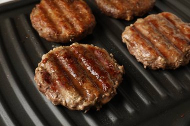 Lezzetli hamburger köfteleri elektrikli ızgarada pişiyor, yakın plan.
