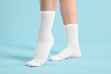 Açık mavi arka planda şık beyaz çoraplı kadın, yakın plan.