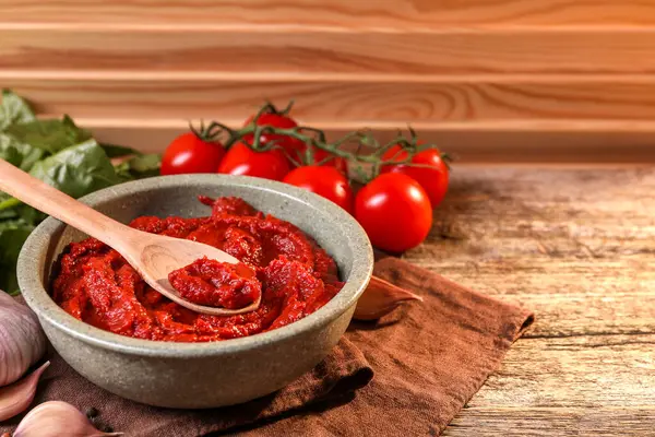 Bir kase lezzetli domates ezmesi, kaşık ve ahşap masa malzemeleri. Metin için boşluk
