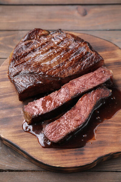 Delicious grilled beef meat on wooden table, closeup