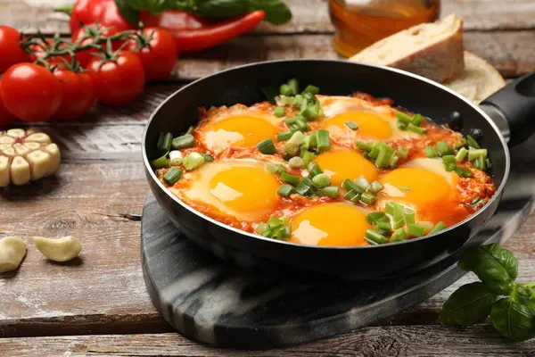 Lezzetli Shakshuka ahşap masada tavada, yakın plan