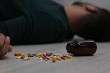 Yerde uyuyan adam, antidepresanlı ters dönmüş şişeye odaklan.