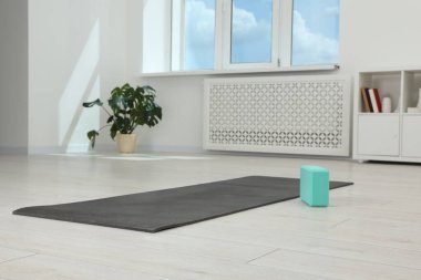 Odada egzersiz paspası ve yoga bloğu var.