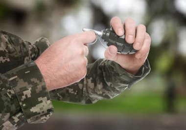 Dışarıda el bombasından emniyet pimini çeken asker, yakın plan.