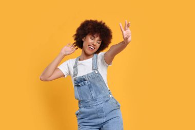 Turuncu arka planda dans eden mutlu genç kadın