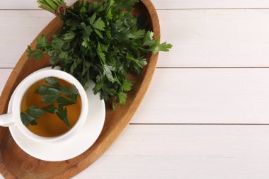 Aromatik bitki çayı ve beyaz ahşap masada taze maydanoz, üst manzara. Metin için boşluk