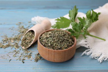 Kurutulmuş maydanoz ve açık mavi ahşap masa üzerinde taze yapraklar. Yakın plan.
