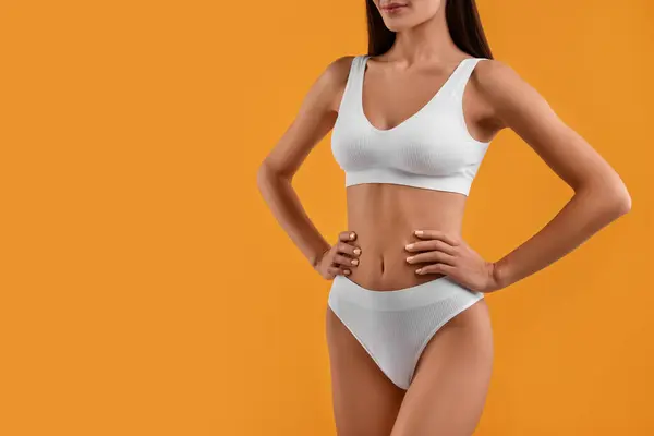 Young woman in stylish white bikini on orange background, closeup. Space for text