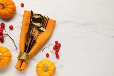 Çatal bıçak takımı, peçete ve sonbahar dekorasyonu beyaz mermer arka planda, düzlük ve metin için yer var. Tablo ayarı