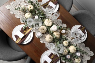 Güzel bir sonbahar sofrası. Tabaklar, çatal bıçak takımı, bardaklar, boş kartlar ve çiçek dekoru.