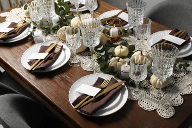 Güzel bir sonbahar sofrası. Tabaklar, çatal bıçak takımı, bardaklar, boş kartlar ve çiçek dekoru.