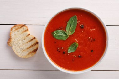 Lezzetli domates kremalı çorba kasede ve ızgara ekmek beyaz ahşap masa üzerinde, düz yatıyordu